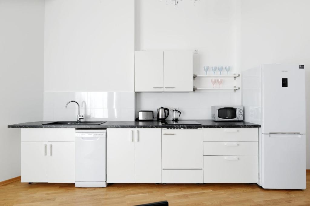 uma cozinha branca com armários brancos e um lavatório em Grand Central City Apartments Mitte Rosenthaler Platz em Berlim