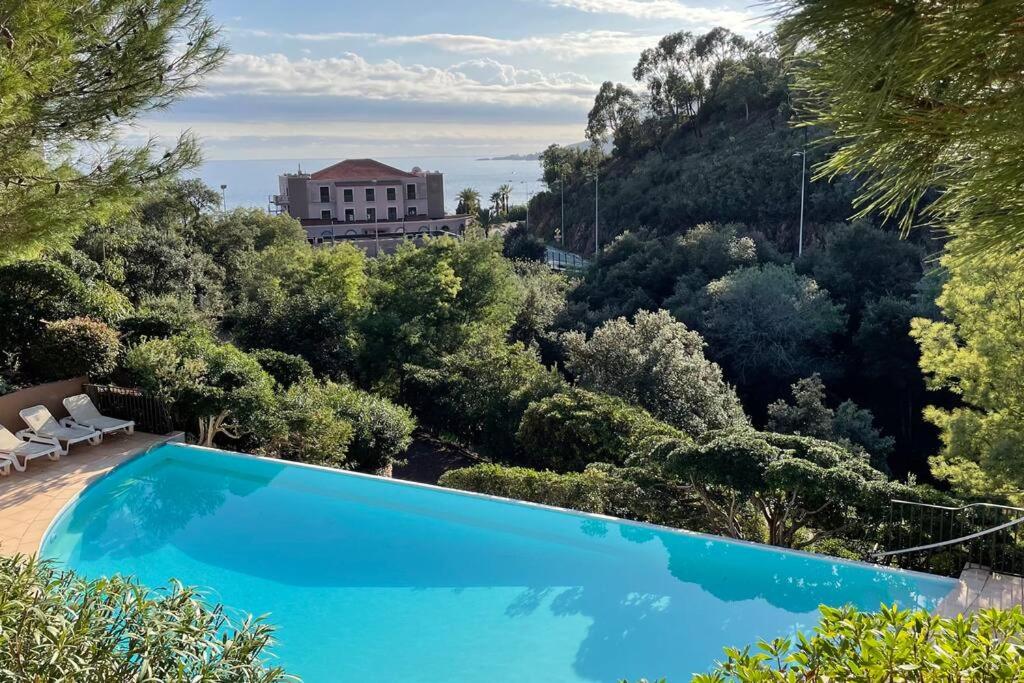 une piscine bleue avec des arbres et un bâtiment en arrière-plan dans l'établissement Casatheoule, à Théoule-sur-Mer