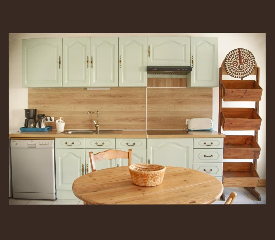 une cuisine avec des armoires blanches et une table en bois dans l'établissement Appart coeur de village - proche des criques, à Port-Vendres