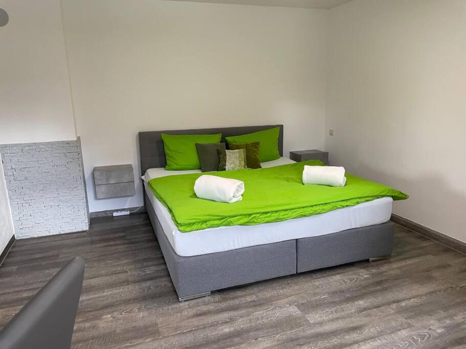ein Schlafzimmer mit einem großen Bett mit grüner Bettwäsche in der Unterkunft Auf dem Land und doch ganz nah (EG) in Krölpa
