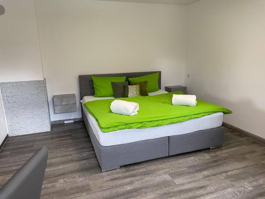 a bedroom with a large bed with green sheets at Auf dem Land und doch ganz nah (EG) in Krölpa