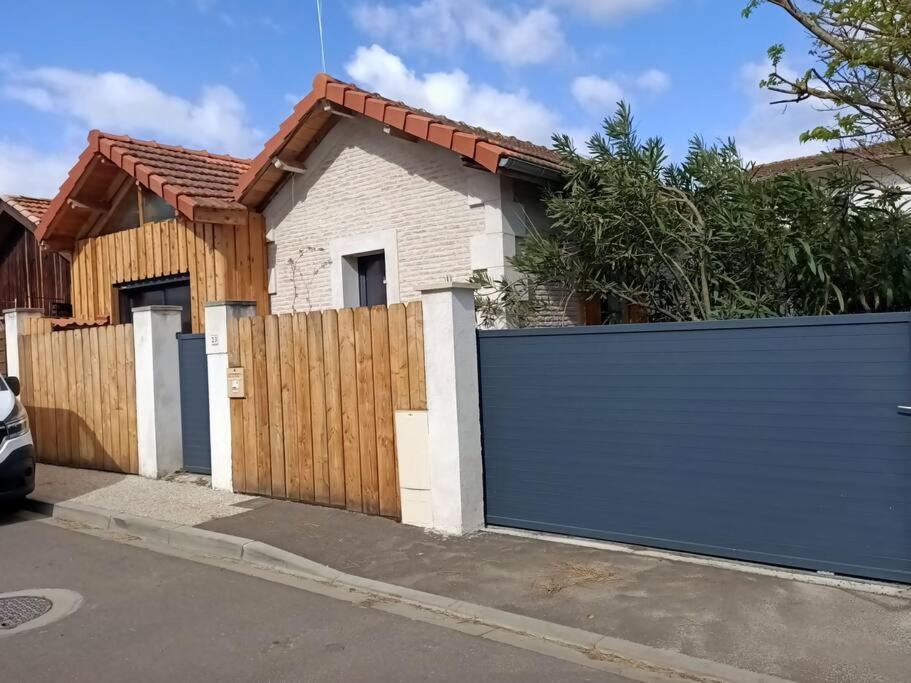 a house with a blue gate and a fence at T3 refait à neuf, patio, wifi et plage in Arcachon