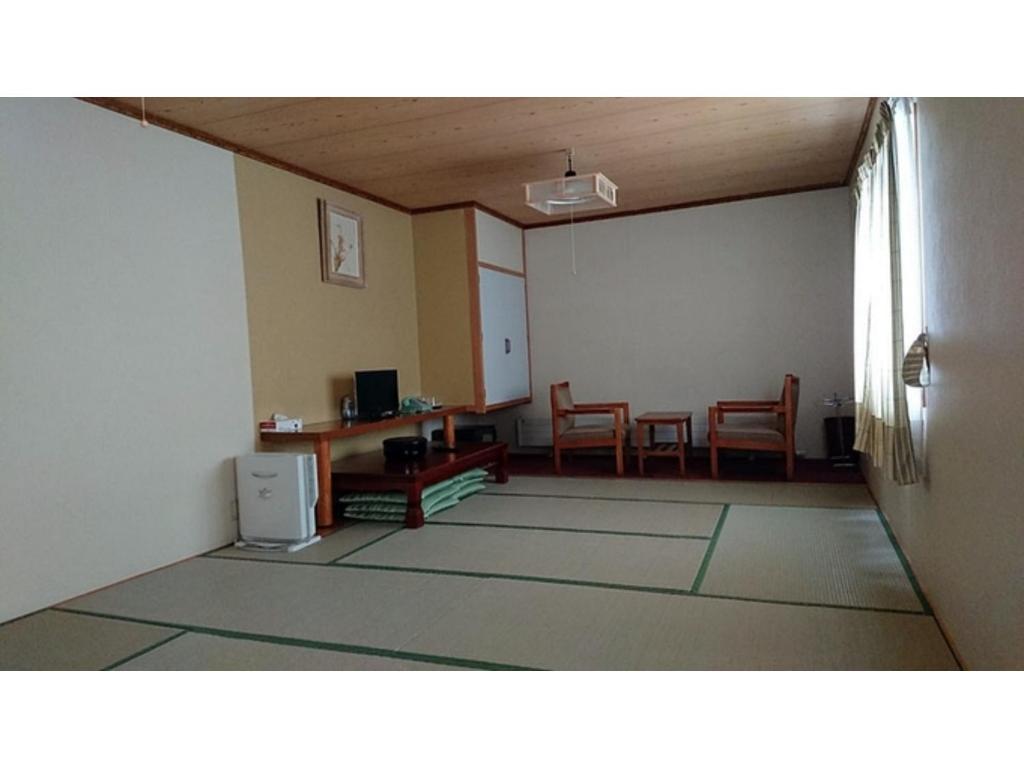 um quarto com uma sala de estar com uma mesa e cadeiras em Onsen Hotel Tsutsujiso - Vacation STAY 03256v em Kitami