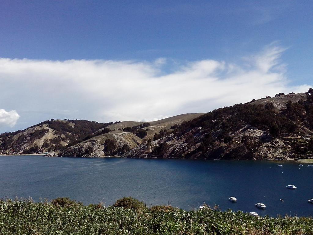 a large blue lake with boats on a mountain at Willka Kuti Hostal - Lado Norte Isla del Sol in Comunidad Challapampa
