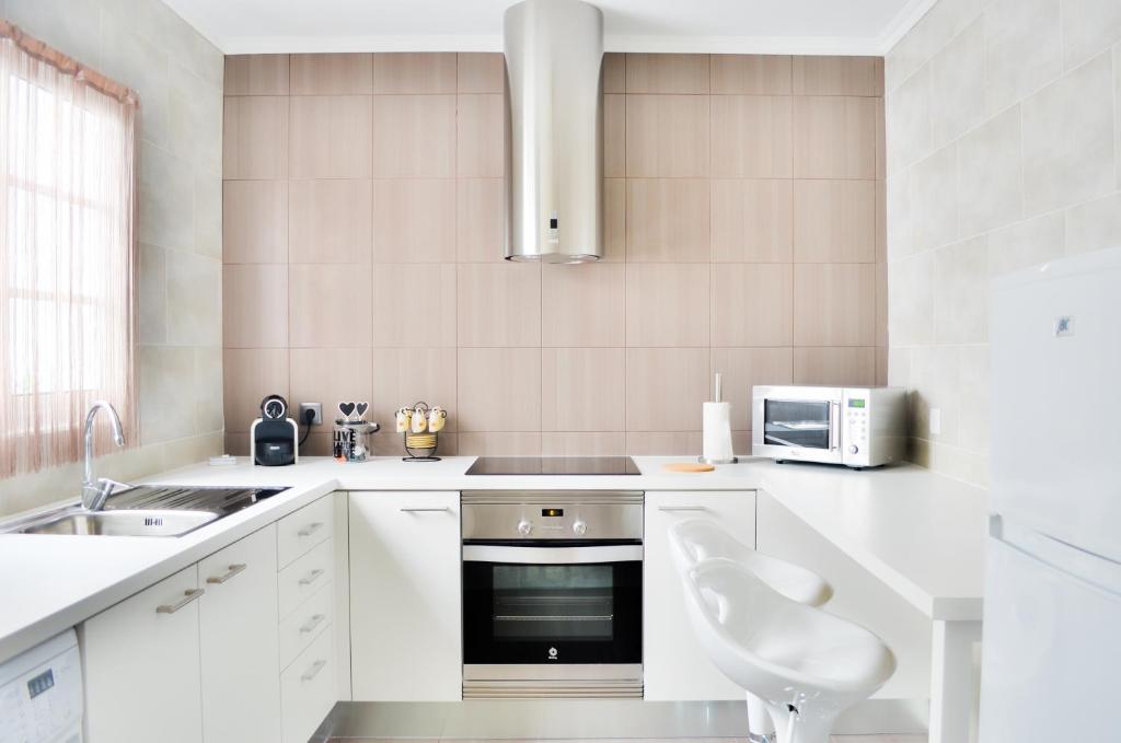 a white kitchen with a sink and a microwave at A Casa do Chafariz in Ribeira Grande