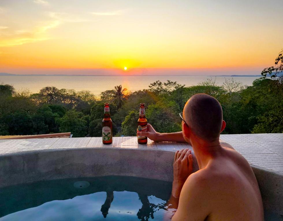 un hombre sentado en una piscina con dos botellas de cerveza en Villa Ometepe en Mérida