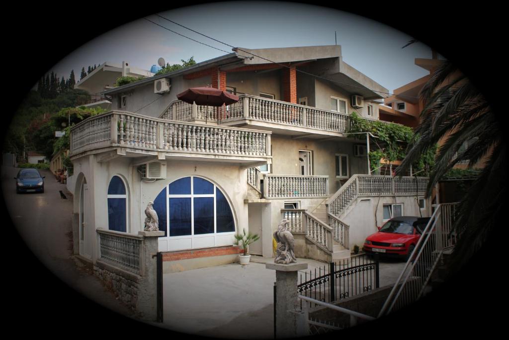 een groot huis met balkons en een rode auto voor de deur bij Marko Apartment in Sutomore
