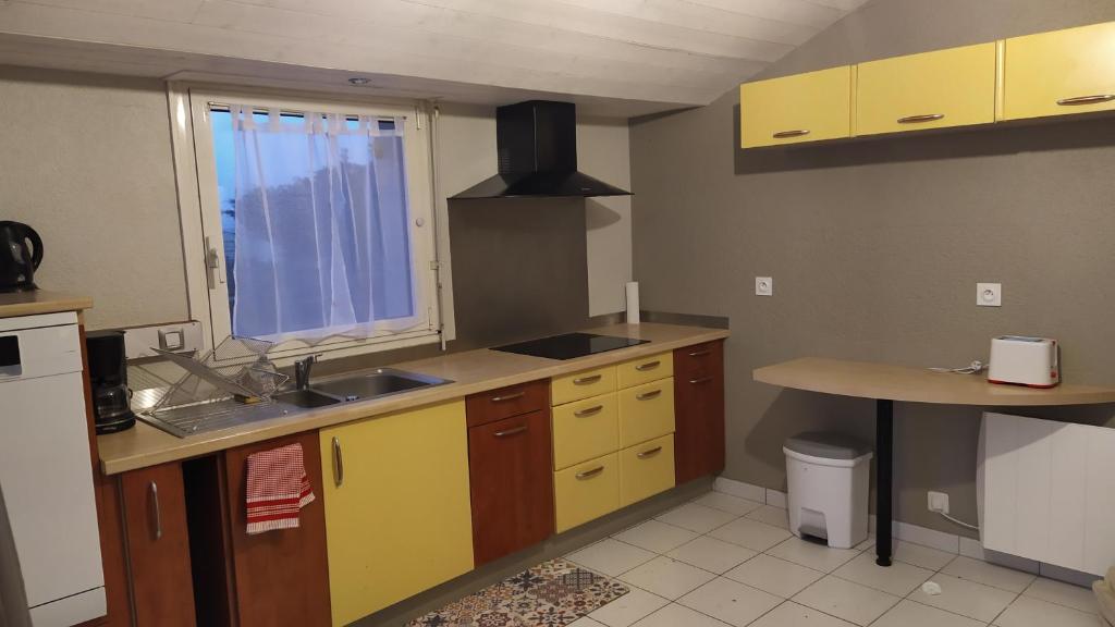 a kitchen with yellow cabinets and a sink and a window at Gite la Péraie - Le Roseau in Treize-Vents