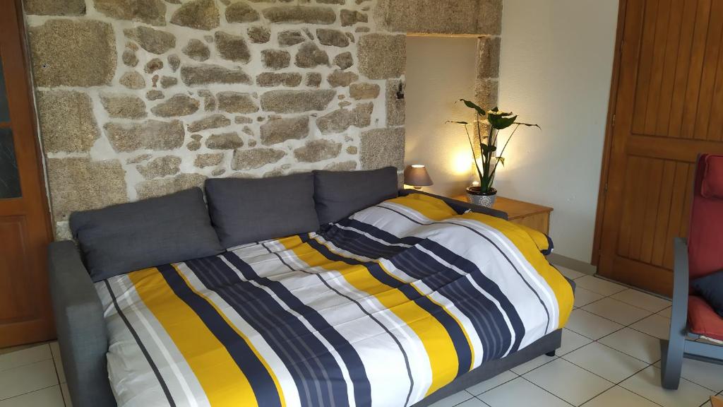 a bed in a room with a stone wall at Gite la Péraie - Le Roseau in Treize-Vents