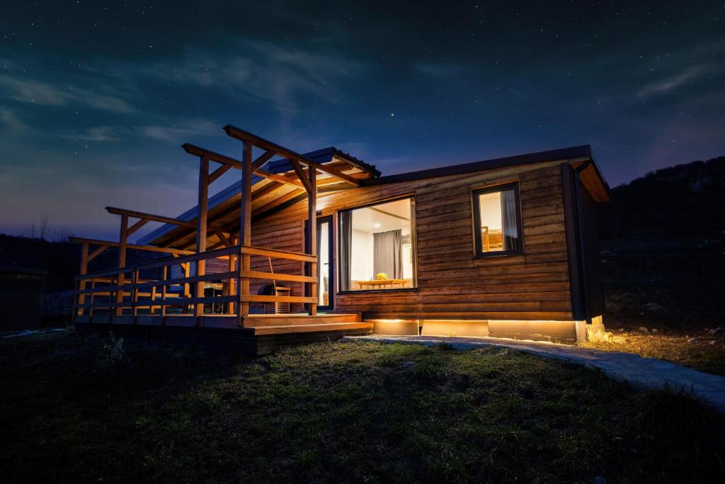 a log cabin with a deck at night at Outdoor Resort Pecka in Mrkonjić Grad