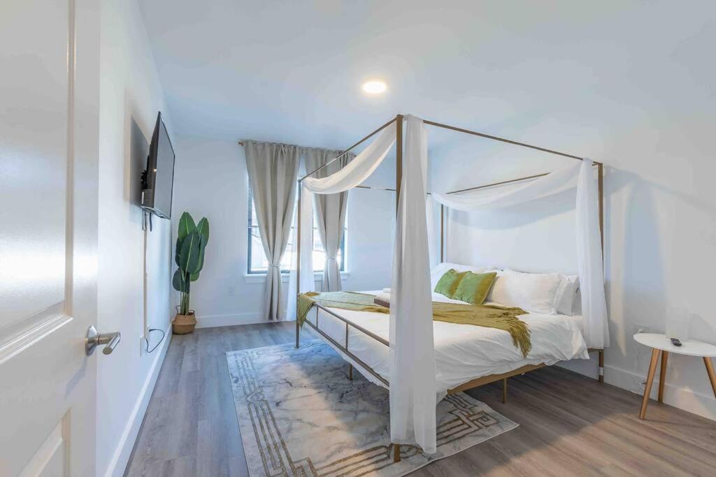 um quarto com uma cama de dossel num quarto branco em 2 bedroom 2 bath Suite, Near American Dream and The Airport, Free Parking, King Bed and 2 Queen Beds, Washer and Dryer em Orange