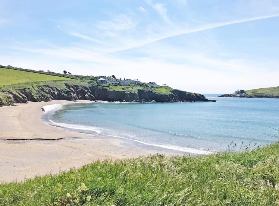 a beach with a house on a hill next to the ocean at Cosy Beachside Cottage in Bigbury