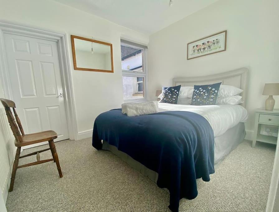 Hotel 64 Bath Road - Central to Cheltenham, a bedroom with a bed with a blue blanket and a chair at 64 Bath Road - Central to Cheltenham in Cheltenham