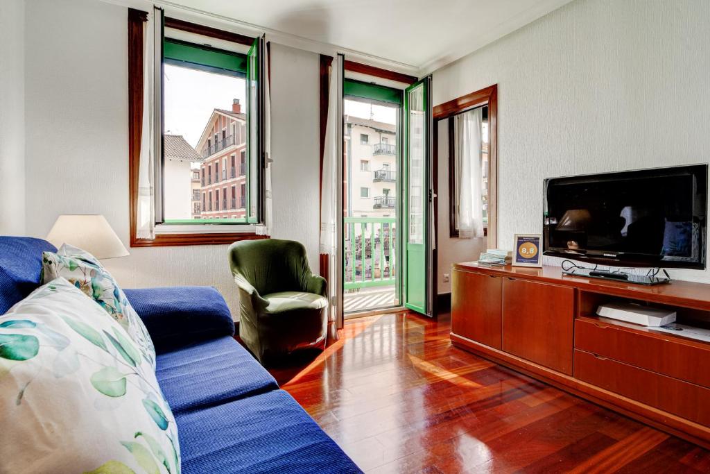 a living room with a blue couch and a tv at Luminoso apartamento en el centro de Hondarribia in Hondarribia