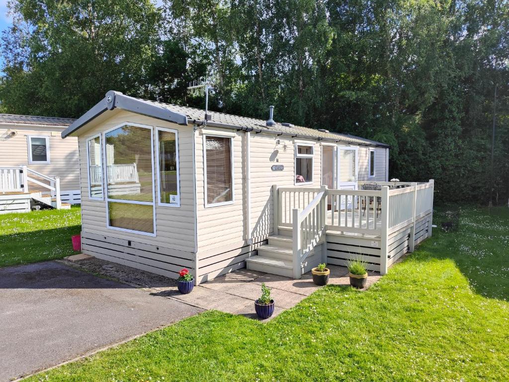 una casita blanca con porche y escaleras en Holiday home sleeps six, en Poole