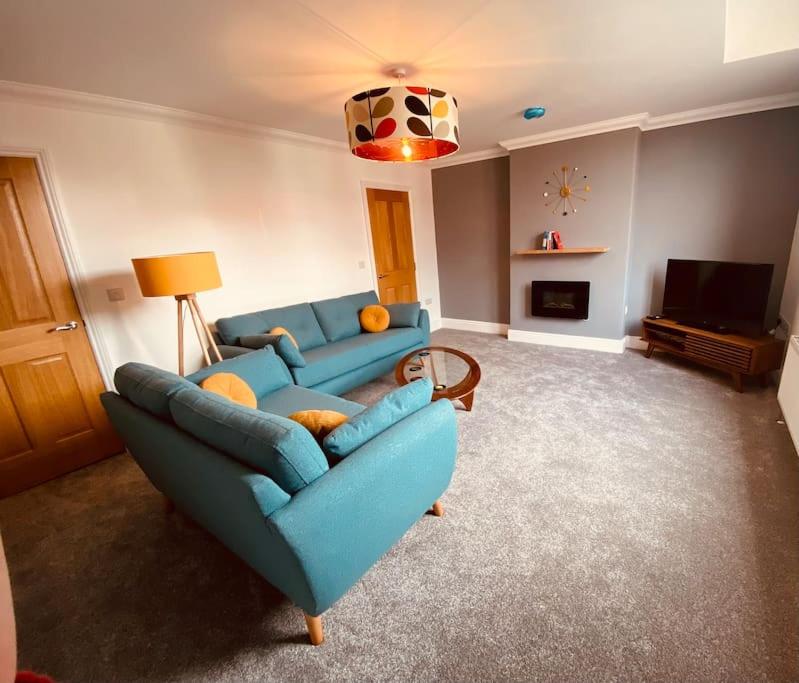 a living room with a blue couch and a television at Luxury 2 bed apt 4 mins from M6 J44 pet friendly, in Carlisle