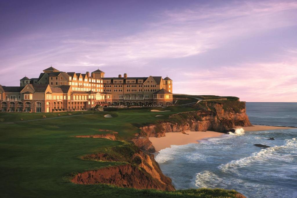 a large building on a cliff next to the ocean at The Ritz-Carlton, Half Moon Bay in Half Moon Bay