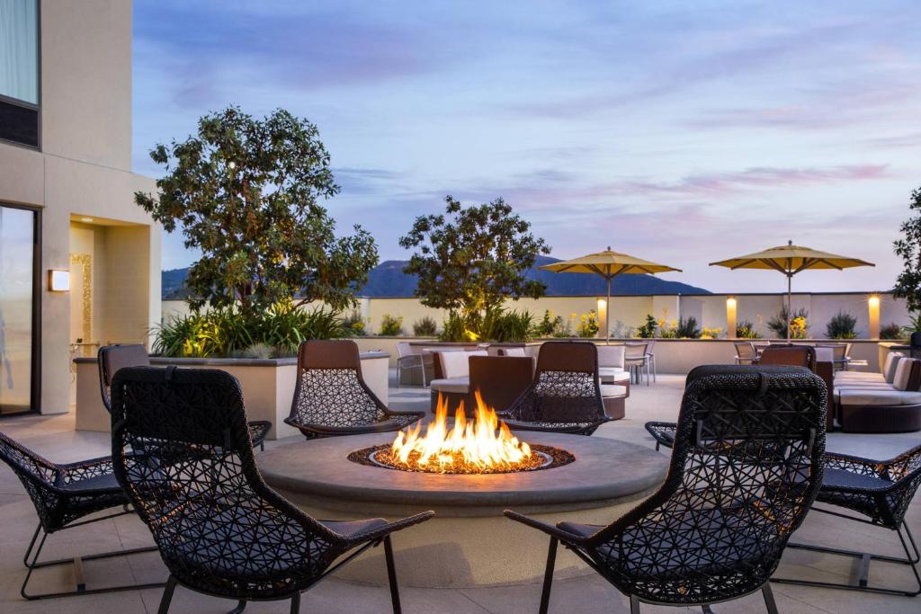 a fire pit on a patio with chairs and umbrellas at SpringHill Suites by Marriott Los Angeles Burbank/Downtown in Burbank