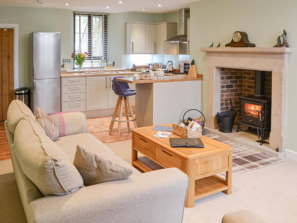 Addycombe Cottage في روثبيري: مطبخ وغرفة معيشة مع أريكة وطاولة
