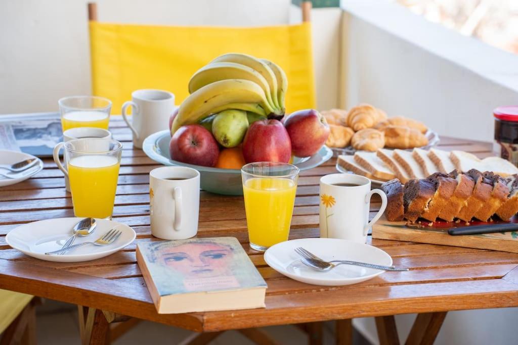 a wooden table with a plate of fruit and orange juice at House of Hapiness in Assos in Asos