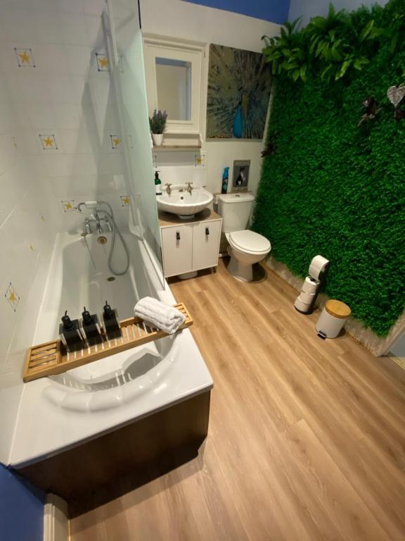 a bathroom with a green wall and a bath tub at Ann Apartments opposite the Pier with sea view in Portsmouth