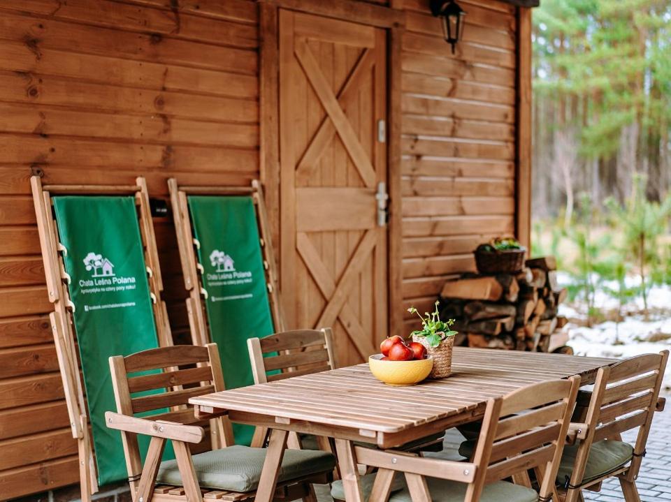 uma mesa e cadeiras de madeira com uma tigela de maçãs em Chata Leśna Polana em Kurzętnik