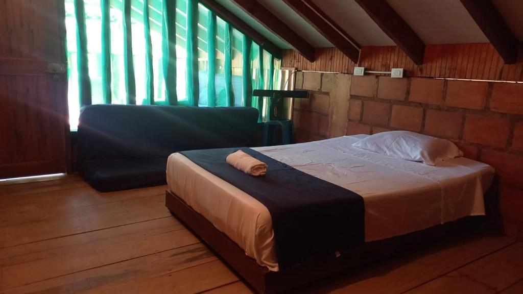 1 cama y 1 silla en una habitación con ventanas en La Cabaña posada turística, en Buenaventura