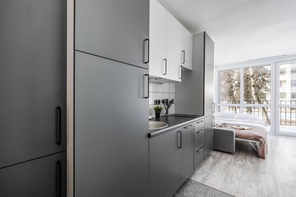a kitchen with white cabinets and a sink at River To The City - Studio 7 Apartment in Vilnius