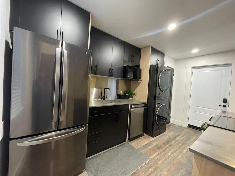 kuchnia z czarnymi szafkami i lodówką ze stali nierdzewnej w obiekcie Charming Century Apartments, Steps to downtown w mieście London