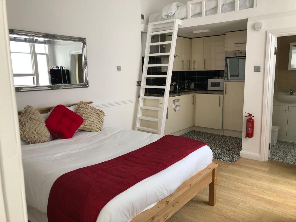 een slaapkamer met een bed met een rode deken en een ladder bij Westbourne Terrace in Londen