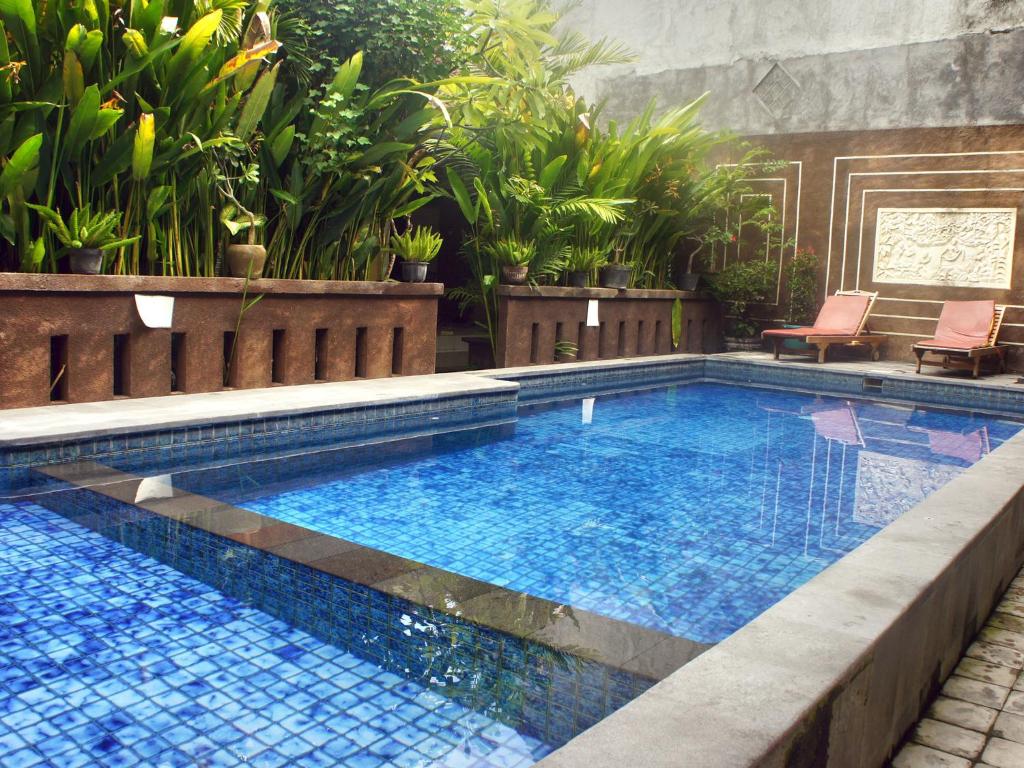 a swimming pool in a yard with plants at Waringin Homestay in Kuta