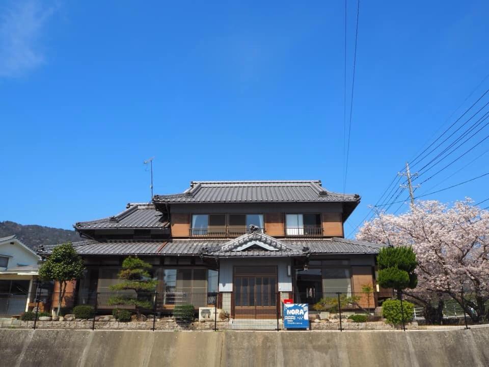 a house with a japanese roof on a street at 体験民宿NORA in Mukaigawa