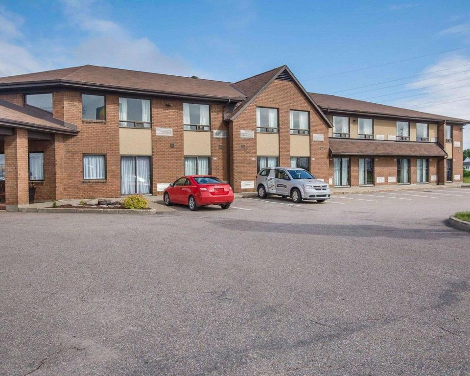 dos autos estacionados en un estacionamiento frente a un edificio en Comfort Inn Baie-Comeau, en Baie-Comeau