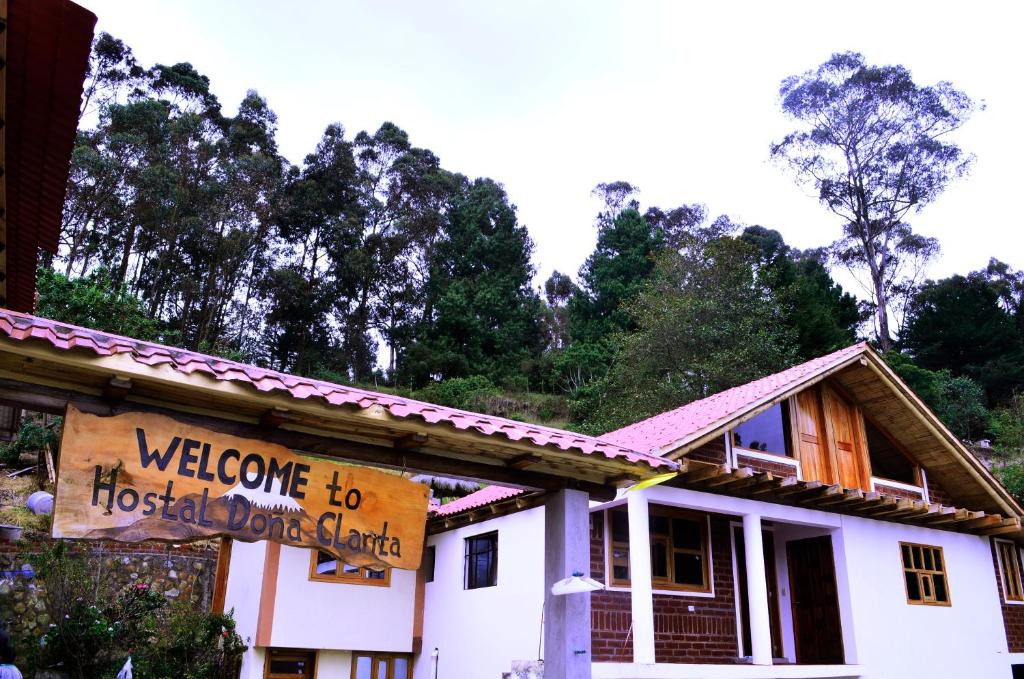 een huis met een bord waarop staat: welkom in Houston Woods bij Hostal Doña Clarita & Vegetarían Food in Chugchilán
