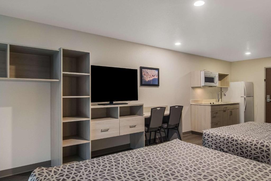 a room with two beds and a desk with a television at WoodSpring Suites Jacksonville Orange Park in Orange Park