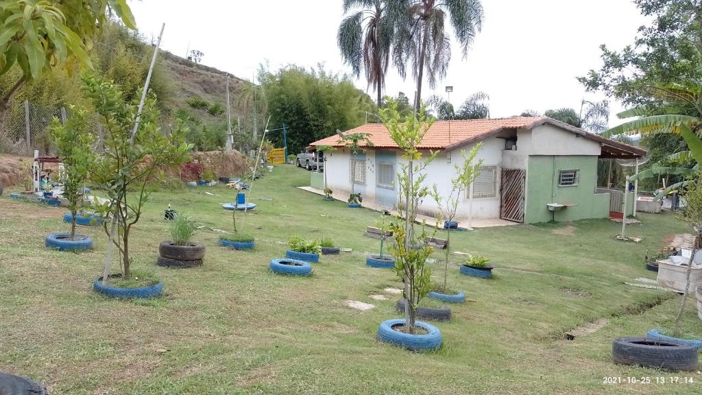 CHÁCARA TERRA dos SONHOS في غواراتينغيتا: مجموعة من الأشجار في ساحة بجوار منزل