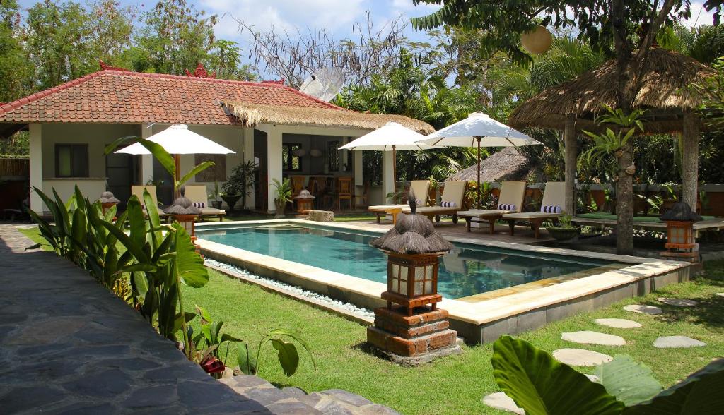 uma piscina com uma casa e um resort em Papaya Guesthouse em Canggu