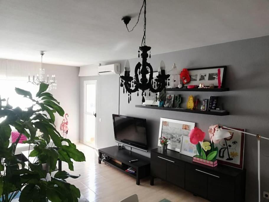 ein Wohnzimmer mit einem Kronleuchter und einem TV in der Unterkunft Apartamento para la felicidad in Roquetas de Mar