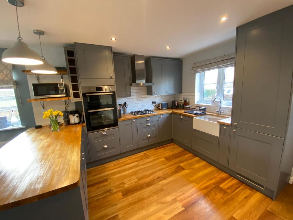 a kitchen with stainless steel appliances and wooden floors at Malmesbury 3 Bedroom Town House in Malmesbury