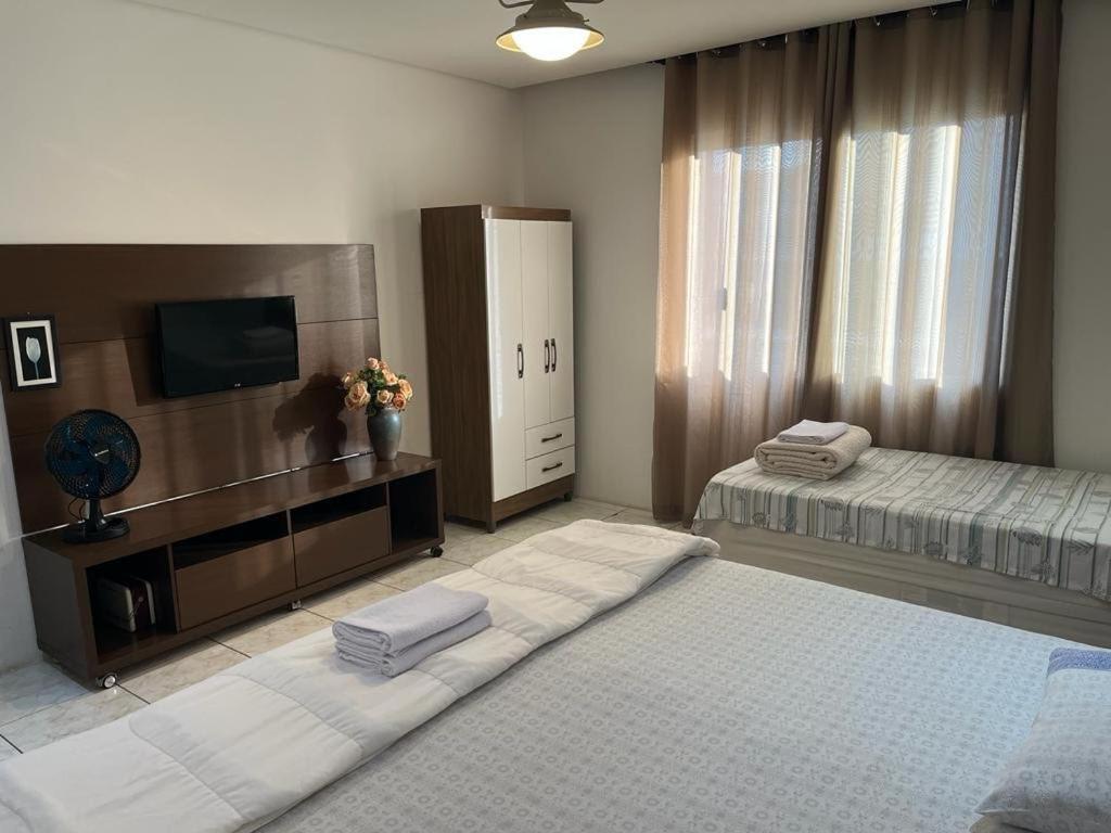 a large bedroom with two beds and a television at Travessa 12 - Suítes centro de Serra Negra - SP in Serra Negra