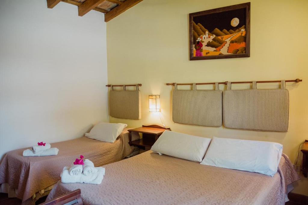 Pokój z dwoma łóżkami i zdjęciem na ścianie w obiekcie El Hospedaje w mieście Cafayate