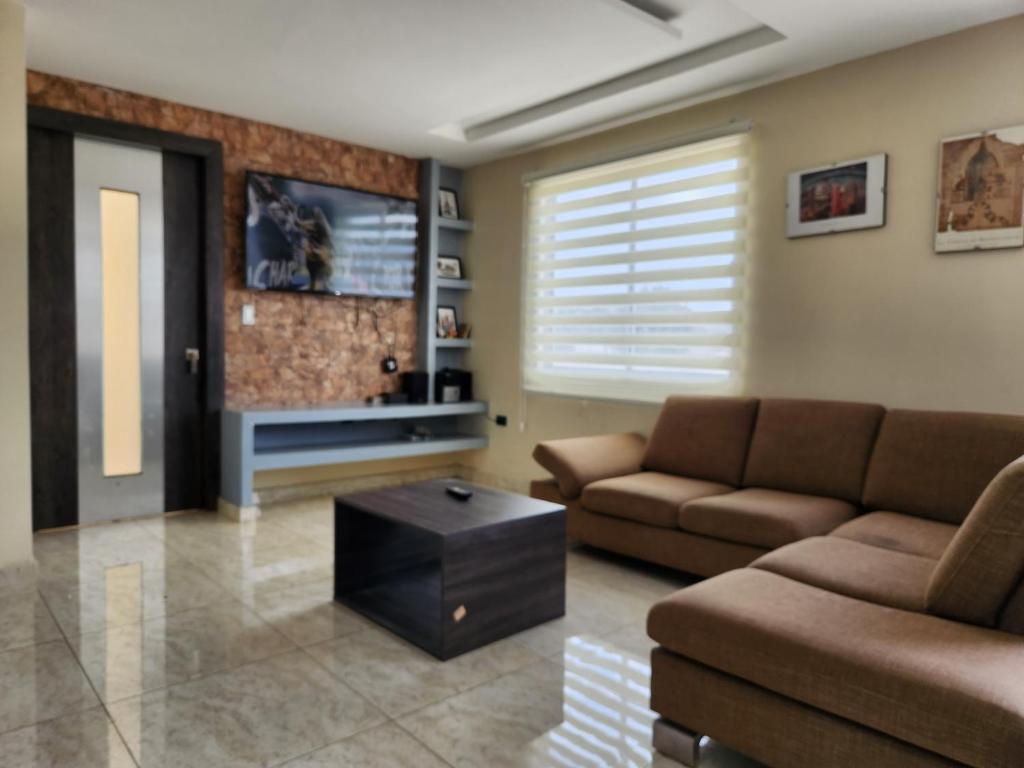 a living room with a couch and a tv at Departamento amplio 2 dormitorios in Cuenca