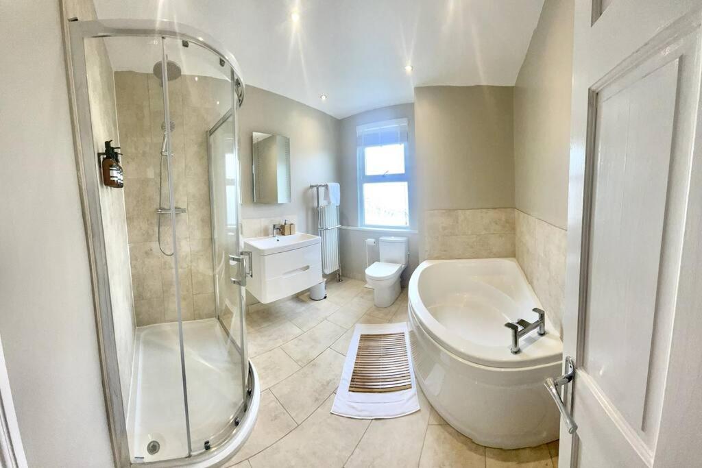 y baño con ducha, bañera y lavamanos. en Spacious Modern Victorian House in Rochester, en Wainscot