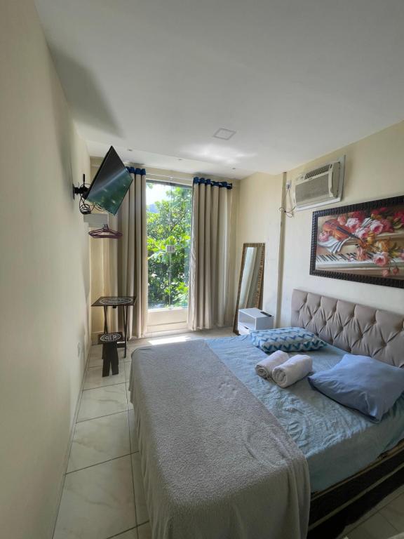 um quarto com uma cama grande e uma janela em Pousada Cantinho do Joá no Rio de Janeiro