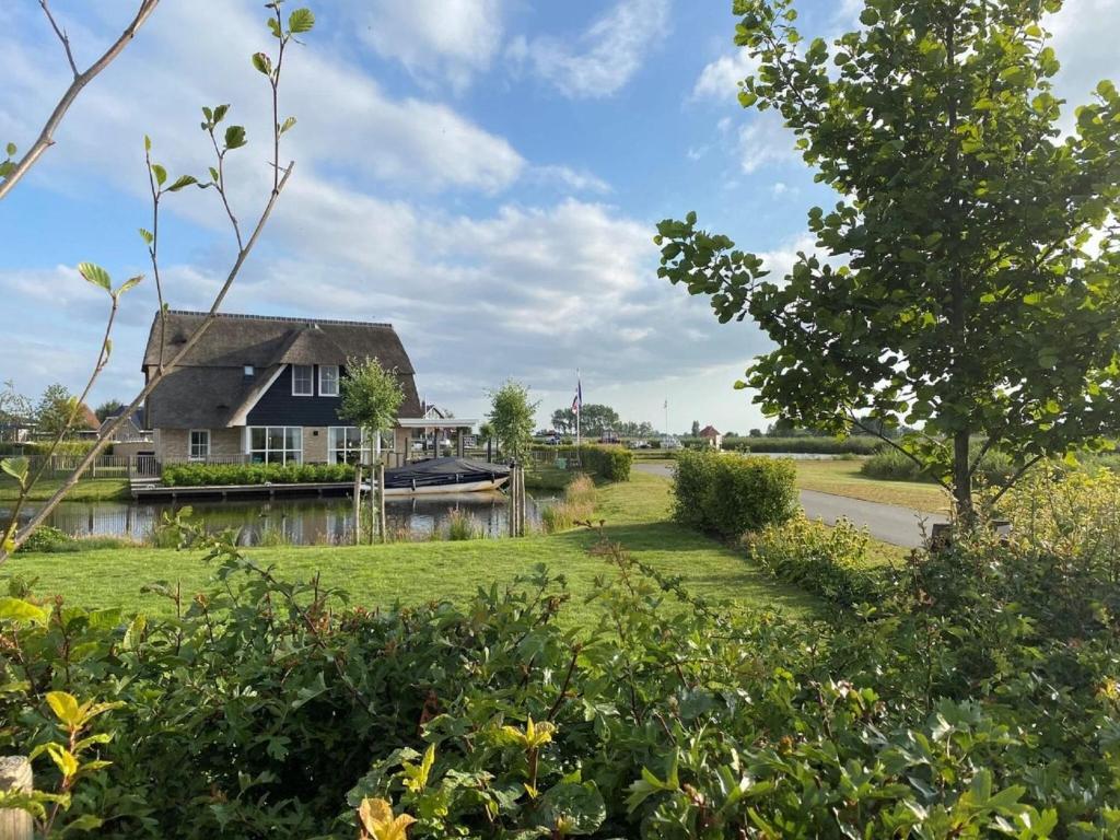 una casa junto a un río con un patio en Beautiful wellness villa with sauna, on a holiday park on the Tjeukemeer, en Delfstrahuizen