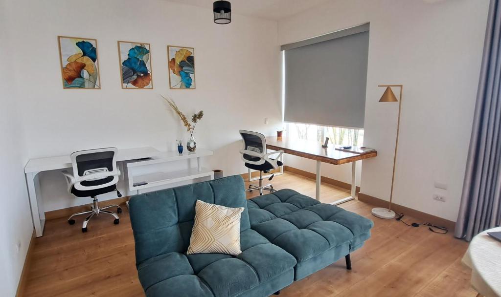 VK Loft - Apartamento en Miraflores في ليما: غرفة معيشة مع أريكة زرقاء ومكتب