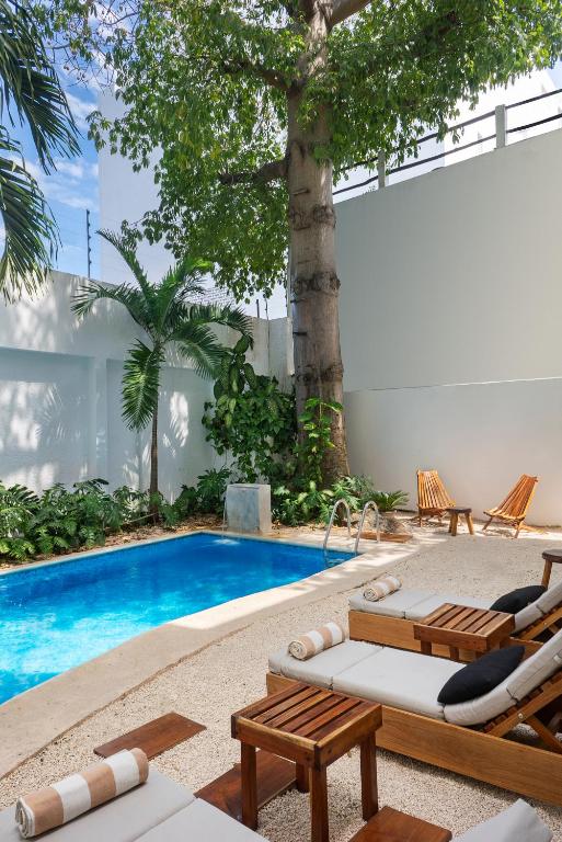 a swimming pool with chaise lounges and chairs next to a pool at Rodina - Hotel Boutique in Playa del Carmen