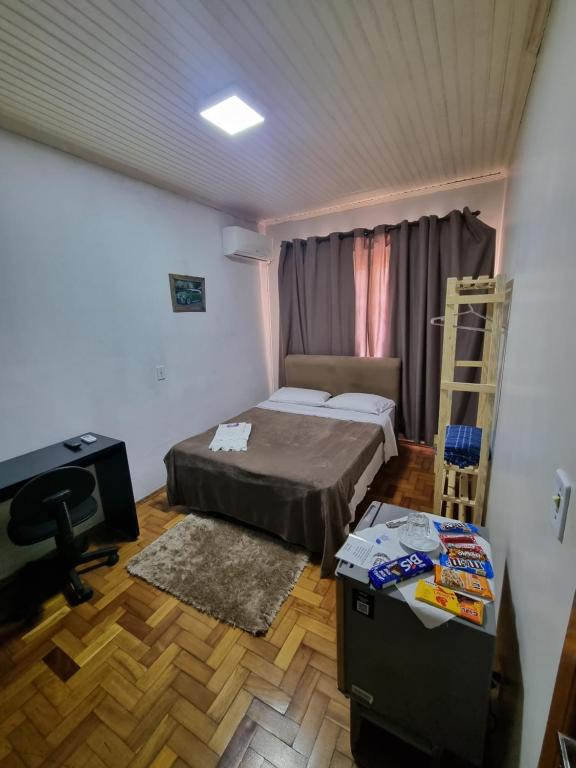 a bedroom with a bed and a desk and a television at CASA DO PINHEIRO in Chapecó