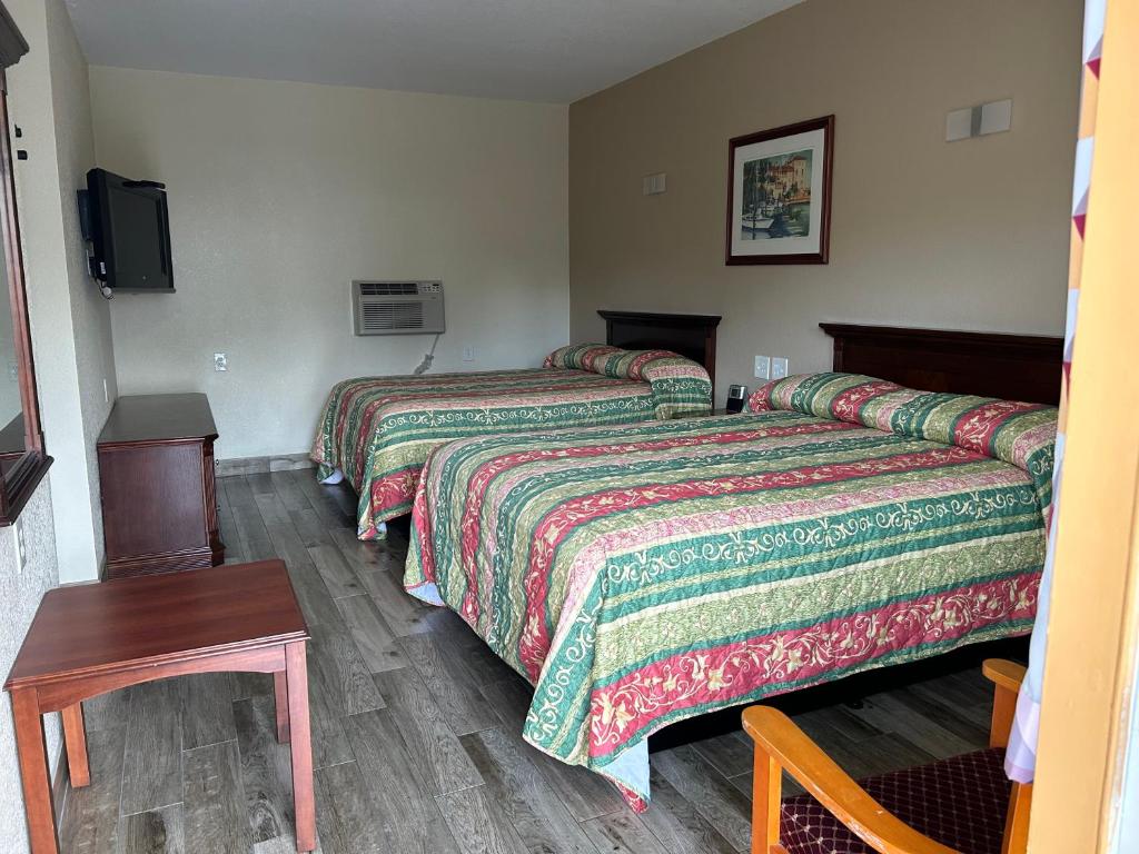 a hotel room with two beds and a tv at Sunshine Inn of Daytona Beach in Daytona Beach