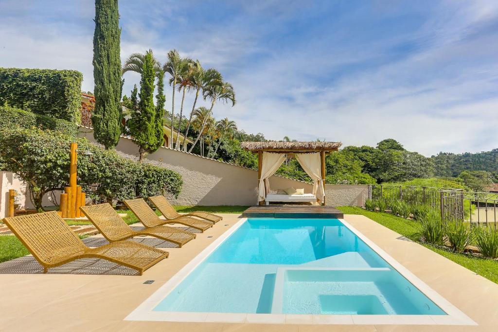 uma piscina com cadeiras e um gazebo em Villa Boréal Hostellerie em Águas de Lindoia